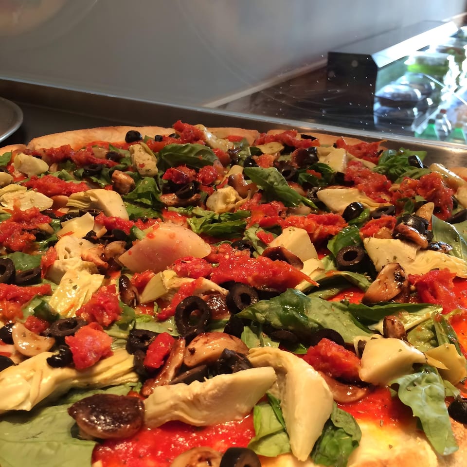 Christian's Pizza with artichokes, olives, spinach, and tomatoes on a red sauce base.