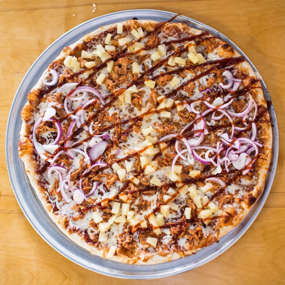 Christian's Pizza BBQ chicken pizza with pineapple, red onion, and a BBQ sauce drizzle.